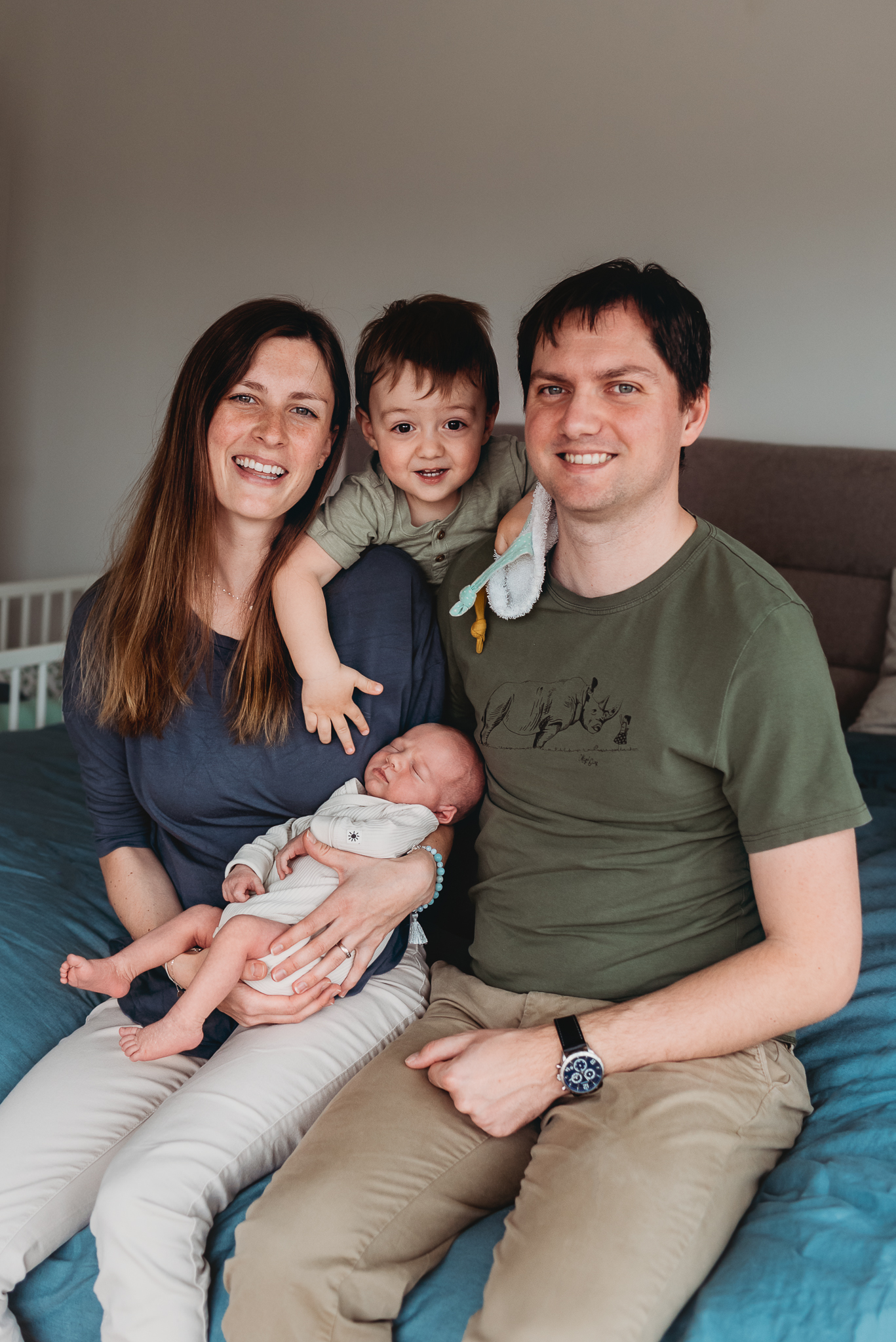 rodina sedící na posteli s novorozeným synem a starším synem