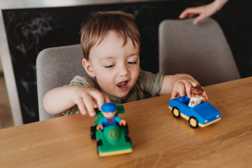 chlapeček si hraje u stolu s lego autíčky