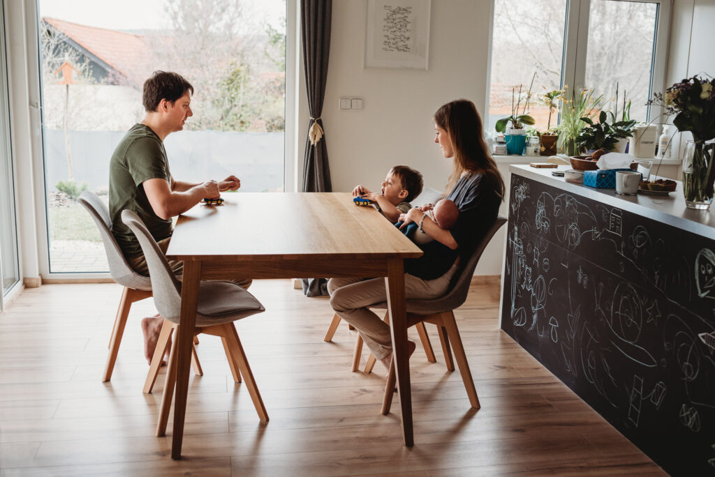 rodina sedící v kuchyni u stolu si posílá lego auta
