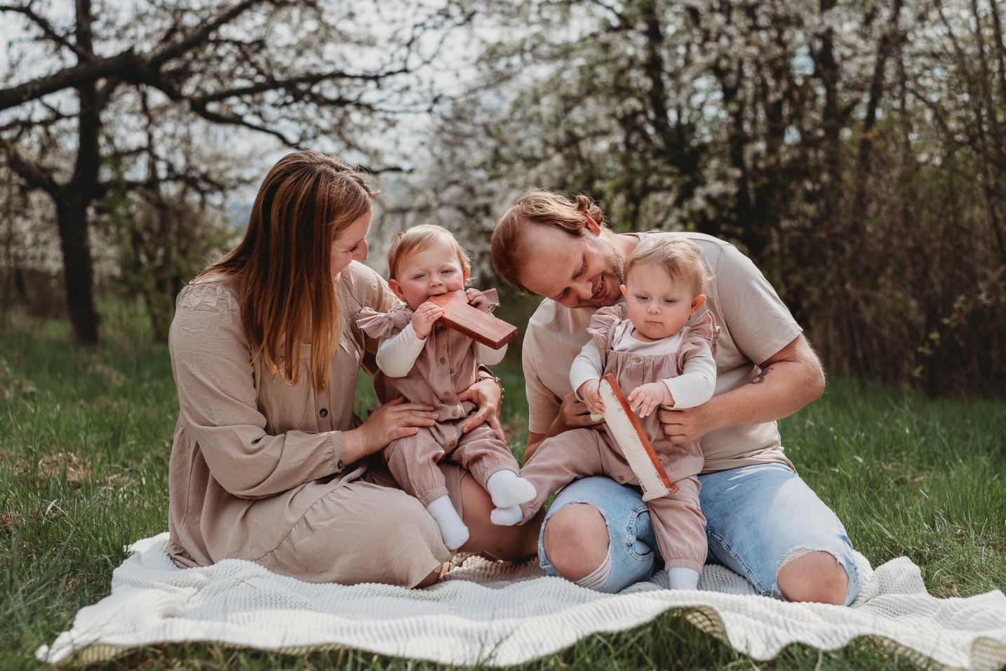 Rodina s dvojčátky slaví první narozeniny na dece v jarních sadech.
