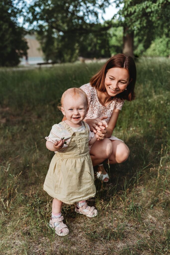 Maminka se usmívá na svou malou dceru v parku.