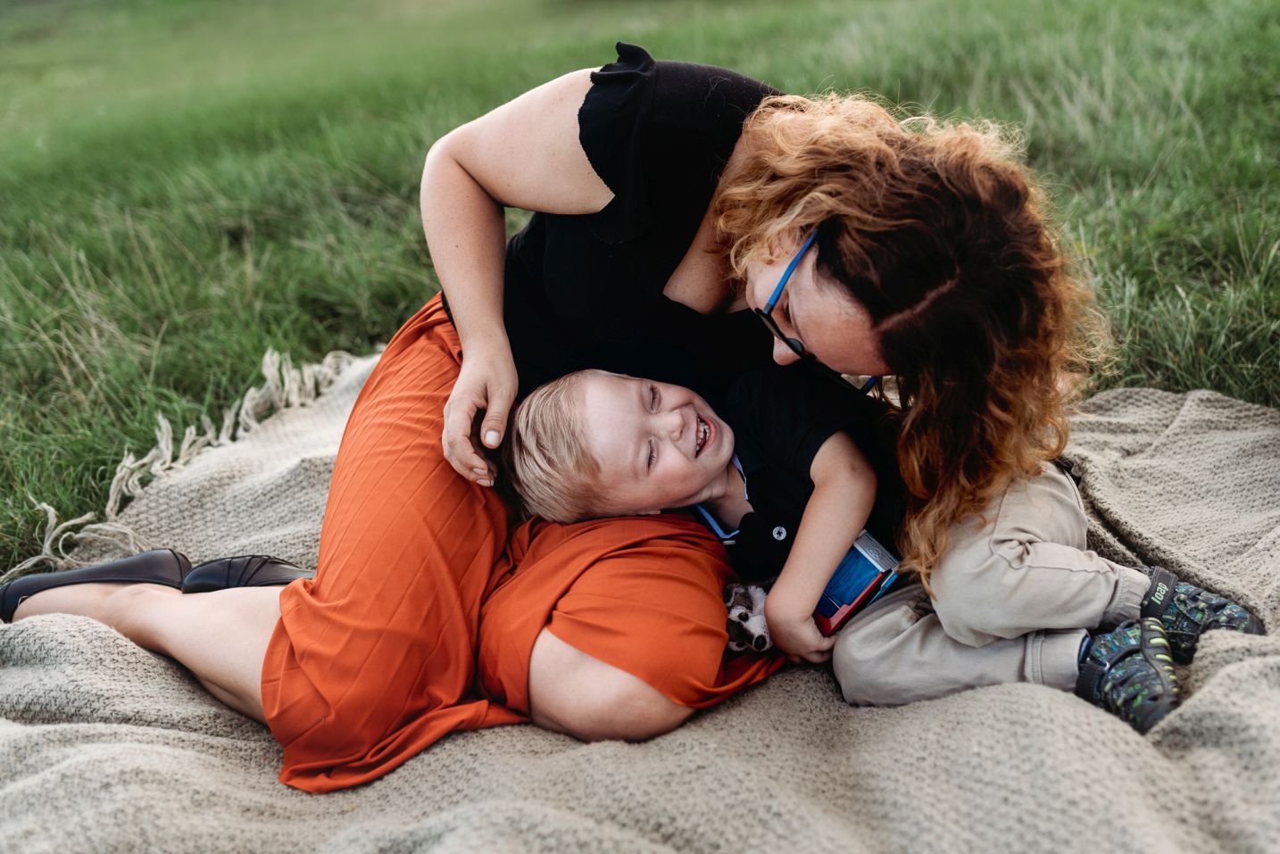 Maminka se směje na syna na dece na louce.