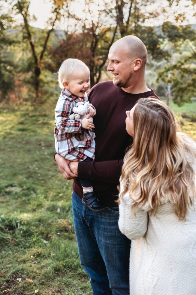 Dcera se v tatínkově náruči usmívá na maminku vedle sebe.