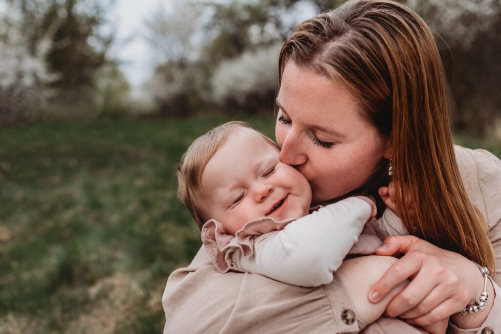 Maminka líbá na tvář svou malou dcerku.