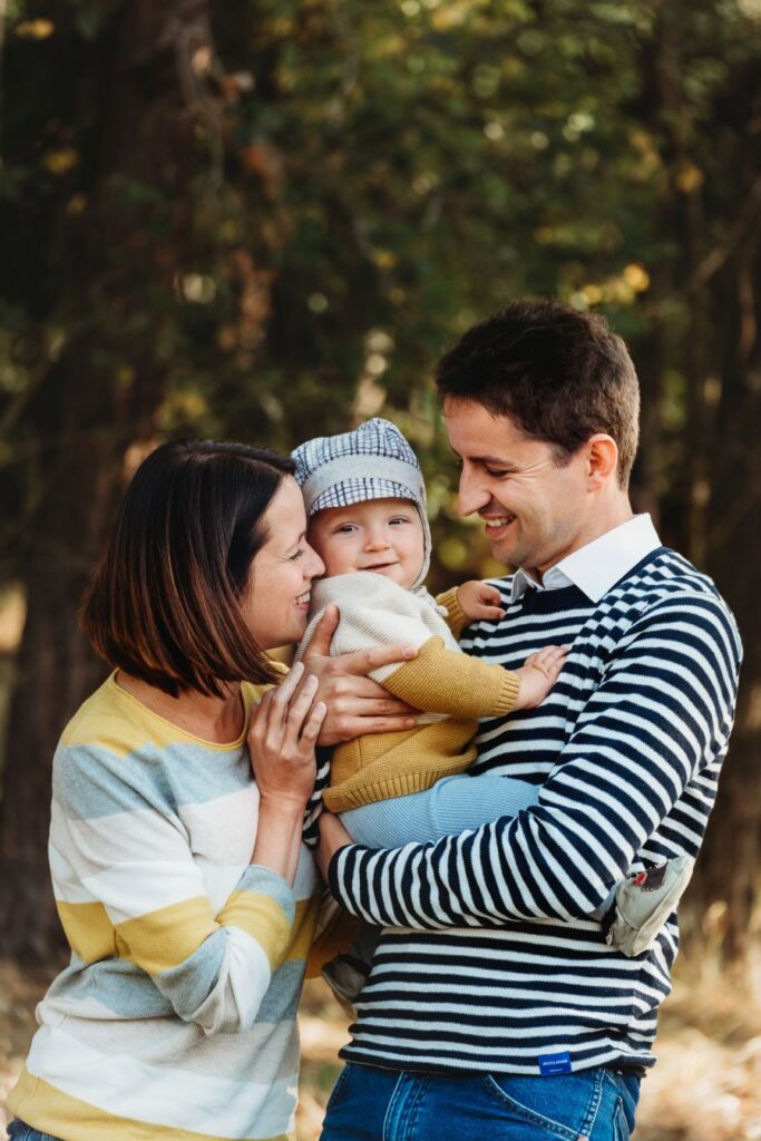 Maminka objímá syna, kterého má tatínek v náruči.