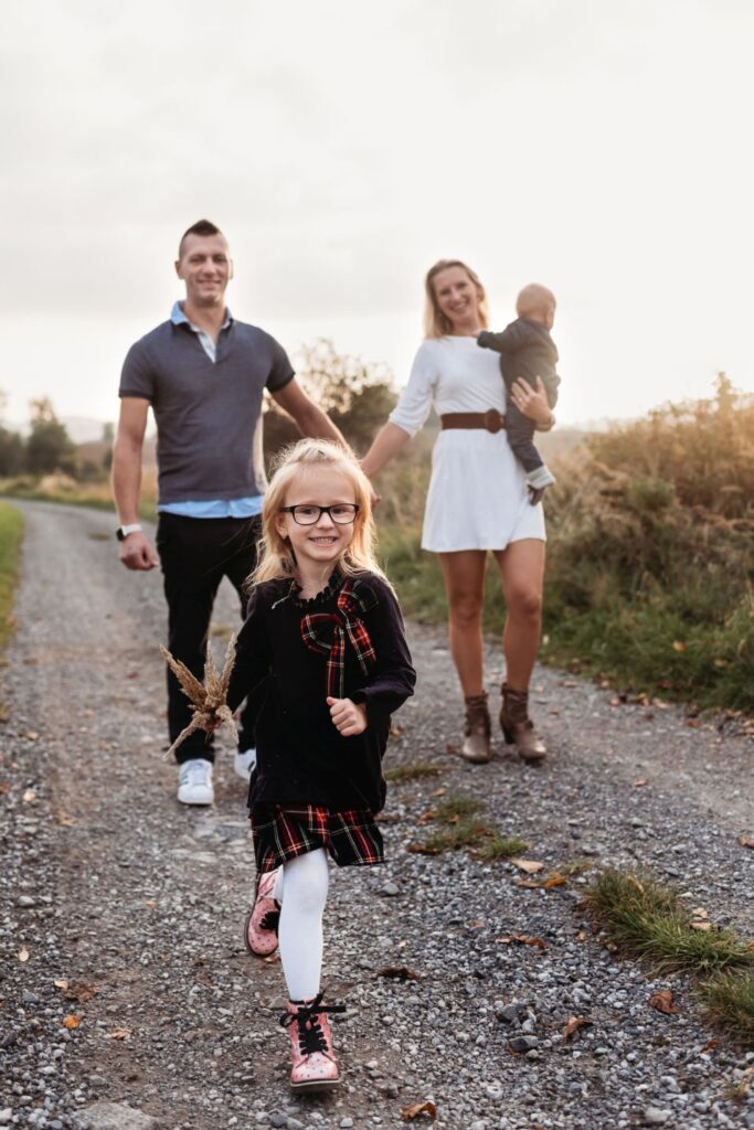 Holčička běží před svou rodinou po cestě.