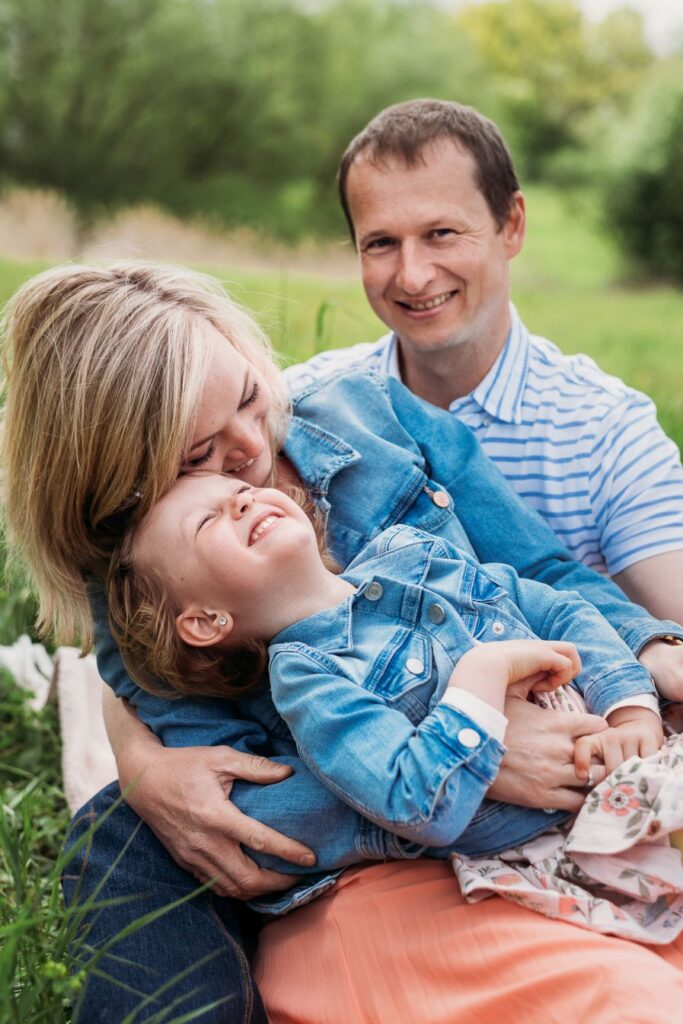 Dcera se mazlí s maminkou v náruči tatínka.