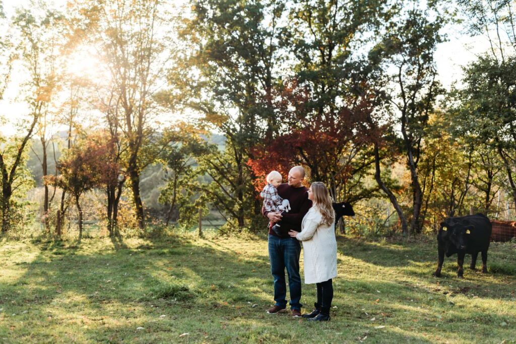 Rodina s dcerou stojí na louce mezi býky.