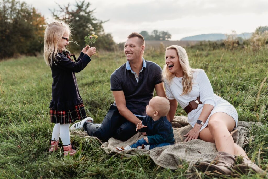 Dcera ukazuje natrhané květiny otci, matce a mladšímu bratrovi.