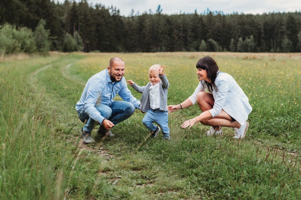 Rodiče na louce chytají malého neposedného syna.