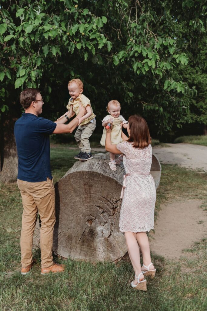 Rodiče drží své děti na kraji obrovské klády.