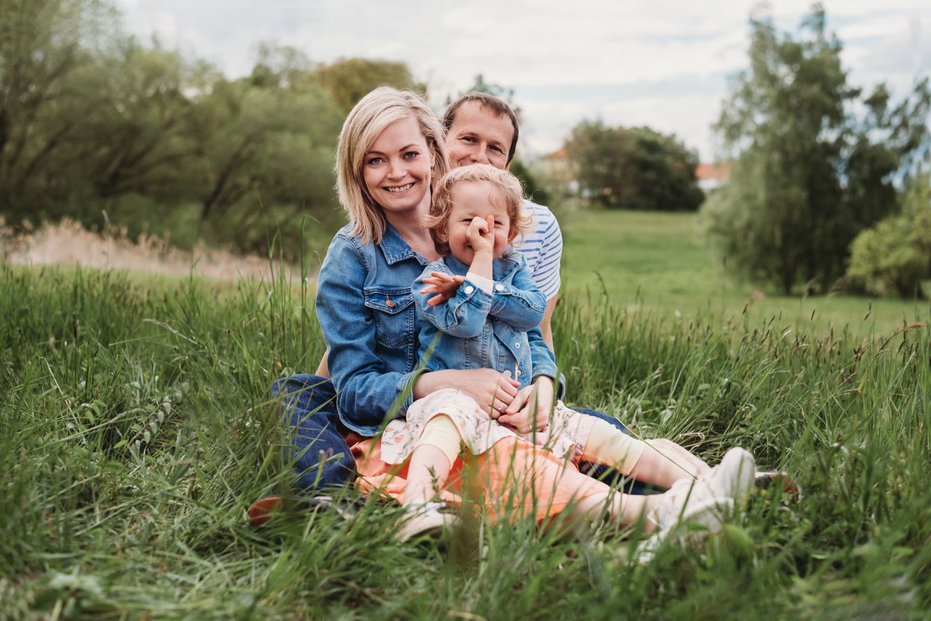 Rodina spolu sedí na louce.